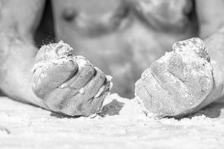 Hands of chef cook working with sticky dough and flour. Homemade concept. Dough and flour scattered all around, close up. Fists of muscular baker or cook full of flour, torso on backgroundの写真素材