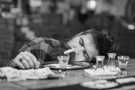 Guy sleep with rolled banknote in nostril, defocused background.の写真素材
