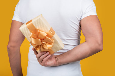 closeup photo of man holding occasion present box. man hold present box isolated on yellowの写真素材