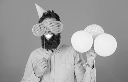 Guy in party hat with air balloons celebrates. Hipster in giant sunglasses celebrating. Man with...