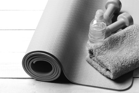 Barbells near water bottle and soft towel on yoga matの写真素材
