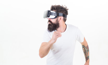 Cyber sport. Guy with head mounted display interact virtual reality. Hipster play virtual sport game. Virtual race. Man bearded gamer VR glasses white background. Virtual reality game conceptの写真素材