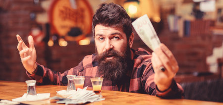 Hipster holds money, cash to buy more alcohol.の写真素材