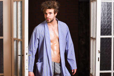 Sexy attractive macho tousled hair coming out through bedroom door. Seductive lover full of desire....