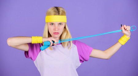 Proper approach to lose weight. Girl hold jumping rope wear bright wristbands. Woman exercising with...