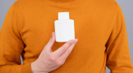 Blank plastic bottle, copy space closeup. Male hands presenting product in bottle.