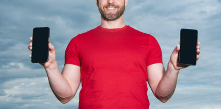 cropped view of man showing phone app on sky background. man showing phone appの写真素材