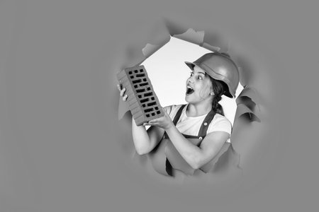 girl in helmet plays builder with brick. building a house. Kid build construction. engineer teen is construction worker. Professional craftsman or workman. International workers day. copy spaceの写真素材