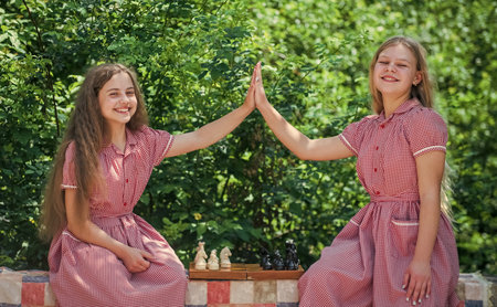 two teen girls playing chess. childhood development. friendship and sisterhood.の写真素材