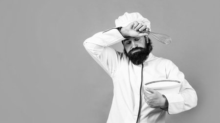 tired brutal hipster in apron finished cooking meal. time for eating. hard baking. concept of housekeeping. mature bearded man wear chef hat. male cook ready for preparing food. exhausted and tiredの写真素材
