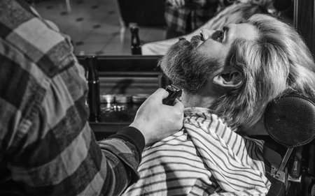 Bearded and stylish. hipster man with beard cutting his hair in a barbershop. Professional hairdressing work. Lifestyle. master barber does the hairstyle and styling with dryer. Concept Barbershopの写真素材