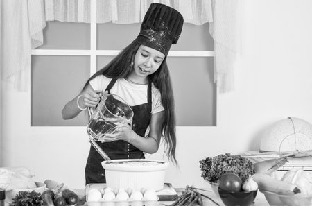 small girl baking in kitchen. kid chef cooking making dough. child prepare healthy food at home and...