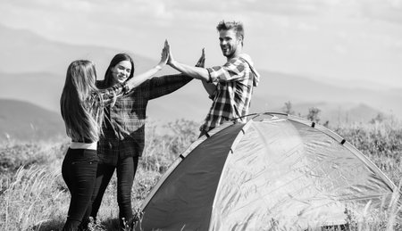 Good job. Teamwork concept. Hiking activity. Friends set up tent on top mountain. Camping equipment. Weekend in mountains. Man and girls having fun in nature. Well done. Camping gear. Camping tentの写真素材