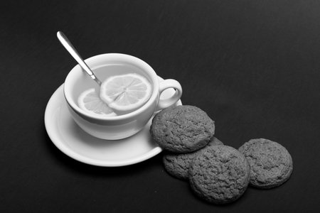 Cookies near tea on dark grey background. Sweet bakery and tea time. Oatmeal biscuits as tasty pastryの写真素材