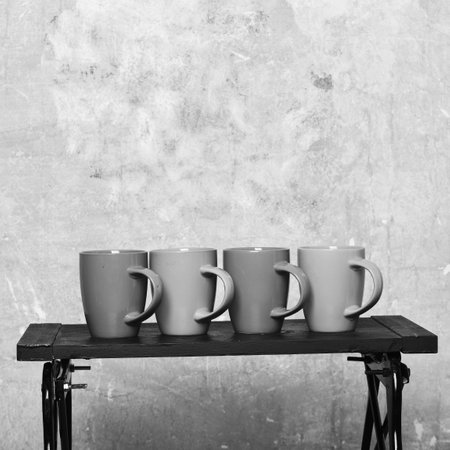 Modern low table with caps of tea or coffee near wall. Cozy office and coffee break concept.の写真素材