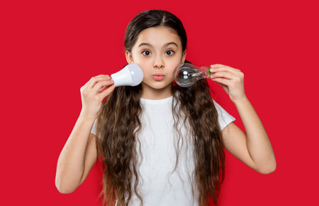 amazed teen girl with lightbulb in studio. teen girl with lightbulb on background.の写真素材