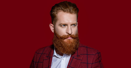 face of man in formalwear suit on background. photo of man in formalwear suit with beard. man in formalwear suit isolated on red. man in formalwear suit at studio.の写真素材