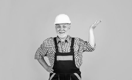 happy senior man builder in helmet on yellow backgroundの写真素材