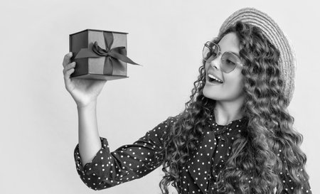 girl smile with curly hair hold present box on yellow backgroundの写真素材