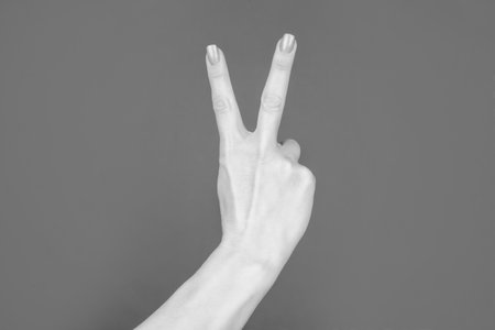 female hand showing peace gesture on red backgroundの写真素材