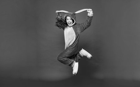 shouting teen girl in soft night suit jumping on red background, comfortの写真素材