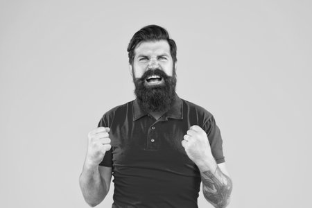 aggressive hipster male with beard on yellow background, angerの写真素材