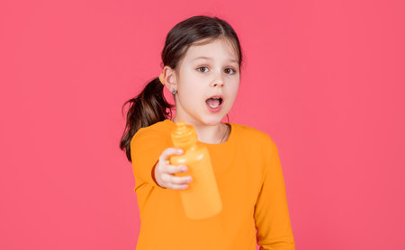 amazed kid hold water bottle on pink backgroundの写真素材