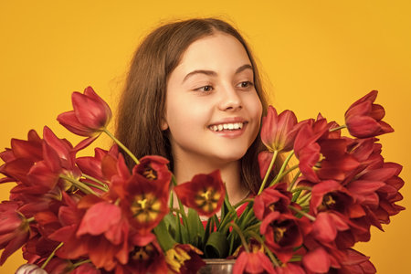 happy child hold spring tulip flowers on yellow backgroundの写真素材