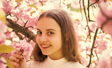 cheerful child at sakura flower bloom in spring