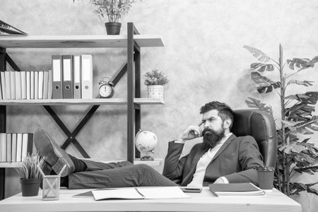 Thoughtful businessman relaxing with legs on office desk, work breakの写真素材