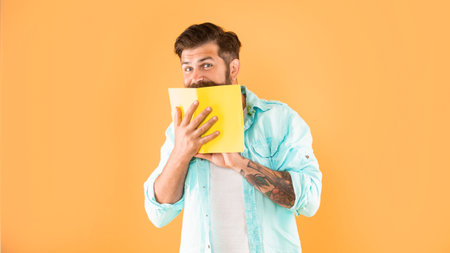 funny positive bearded man behind planner on yellow background, fun