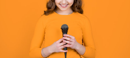 cropped view of teen child with microphone on yellow backgroundの写真素材