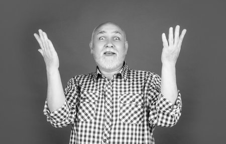 amazed senior man or grandfather in checkered shirt on red backgroundの写真素材