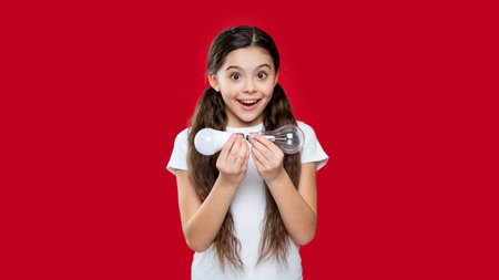 photo of amazed girl with energy saving bulb. girl with energy saving bulb isolated on red.の写真素材