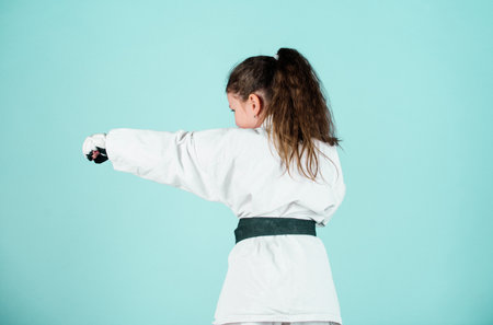 Self defence skills. Karate gives feeling of confidence. Strong and confident kid. She is dangerous. Girl little child in white kimono with belt. Karate fighter ready to fight. Karate sport conceptの写真素材