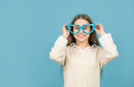 cheerful kid in party glasses on blue background with copy space, childhoodの写真素材