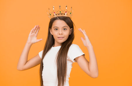 Her design is perfect. confident child in queen crown. rich royal accessory. dream about future wealth. happy childhood. small girl looking gorgeous. fashion and beauty. pride. completely egoistの写真素材