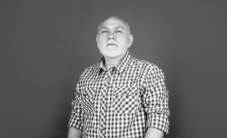 serious senior man or grandfather in checkered shirt on red backgroundの写真素材