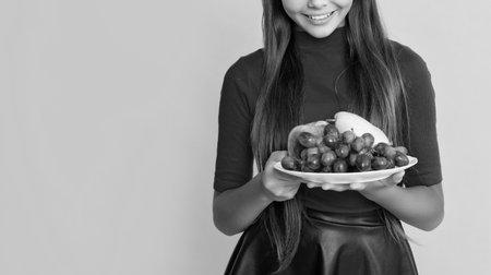 happy girl hold fresh fruit plate on yellow backgroundの写真素材