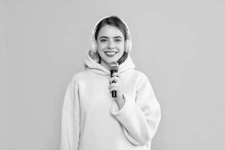 happy young girl in headphones with microphone on yellow backgroundの写真素材