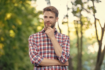 cheerful young man in checkered shirt outdoorの写真素材
