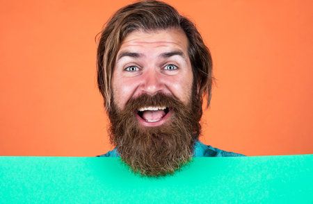 Our products are on sale. barber concept. happy hipster with beard at paper sheet. empty place for copy space. need help. bearded man holding placate. wanted. empty paper for your informationの写真素材