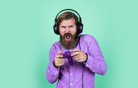 mature bearded guy has long hair wearing headphones use tv game console, digital age