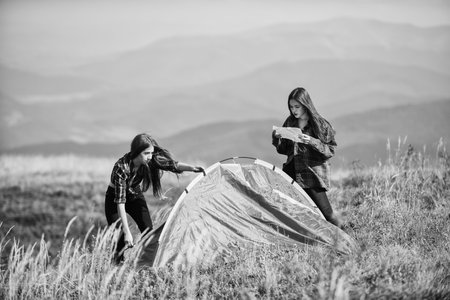 Totally free. family camping. reach destination place. friends spend free time together. mountain tourism camp. two girls pitch tent. wanderlust discovery. hiking outdoor adventureの写真素材