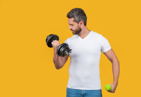 strong sport man hold dumbbell isolated on yellow with copy space. strong sport man hold dumbbellの写真素材