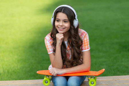 smiling teen girl with skateboard outside. photo of teen girl with skateboard listen music