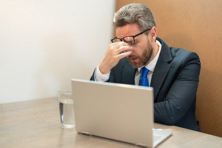 tired overworked businessman has headache while working. overworked businessmanの写真素材