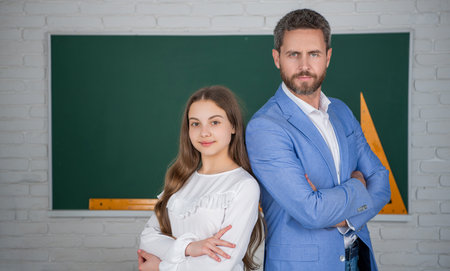 smiling child standing at blackboard with teacherの写真素材
