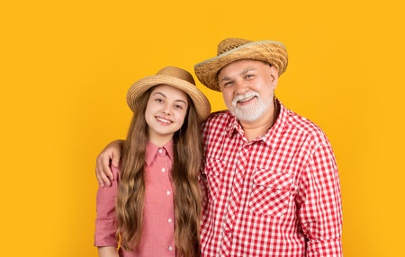 happy teen girl with grandfather in straw hat on yellow backgroundの写真素材