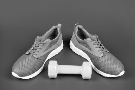 sporty blue sneakers pair with dumbbell on blue background, sport accessory.の写真素材